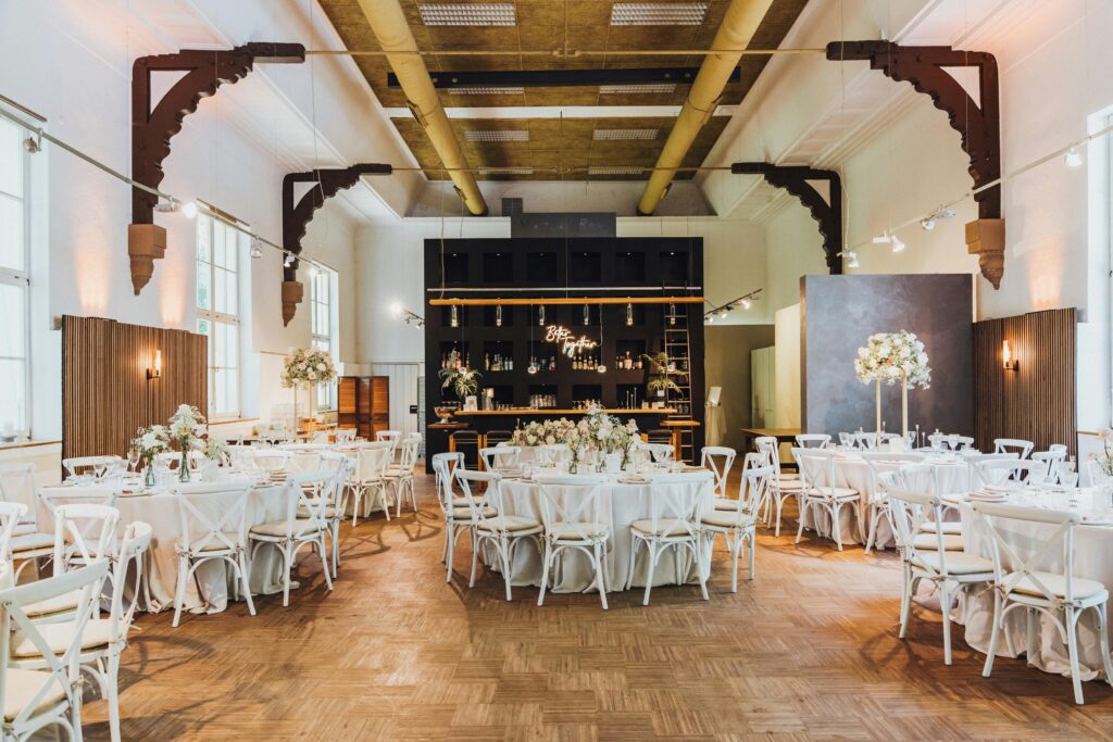 A beautifully decorated indoor wedding reception with floral arrangements and white decor.